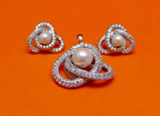 Picture of “Pearl on Love Knot” set of pendant and stud earrings in sterling silver, a single cultured pearl framed by a love knot of round cubic zirconia